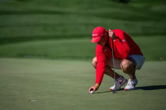 Ohio State Men's Golf player placing ball on the green