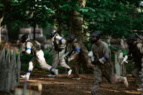 A group of paintball players walking across the forest.