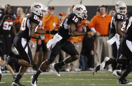 Oklahoma State's Perrish Cox, center, runs past his bench on his way to a touchdown against Colorado on a 67-yard punt-return in the first quarter of an NCAA college football game in Stillwater, Okla., Thursday, Nov. 19, 2009. (AP Photo/Sue Ogrocki)