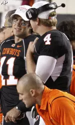 Injured Oklahoma State quarterback Zac Robinson talks with reserve quarterback Brandon Weeden