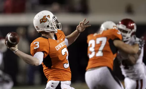 Oklahoma State quarterback Brandon Weeden, left, passes against Oklahoma in the second quarter of an NCAA college football game in Stillwater, Okla., Saturday, Nov. 27, 2010. (AP Photo/Sue Ogrocki)