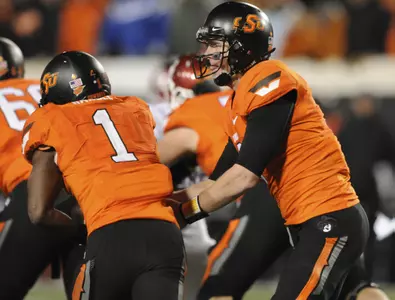 Oklahoma State quarterback Brandon Weeden, right, hands off to running back Joseph Randle, left, during the first half. (AP Photo/Brody Schmidt)