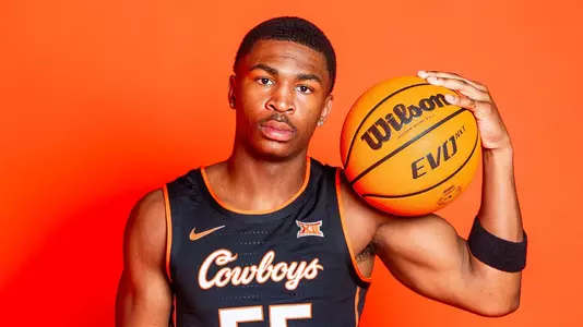 Jacob Walker wearing a black OSU jersey poses with a basketball against an orange backdrop