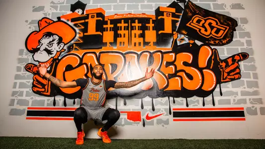 Jordan Burks poses for a picture in front of an OSU mural