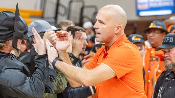 Head coach Steve Lutz high-fives students after a win in Gallagher-Iba Arena