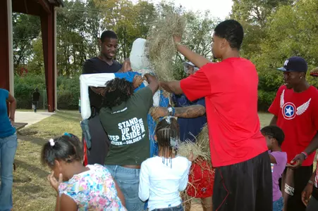 Demarco Cox helps children build a scarecrow for their gareden.