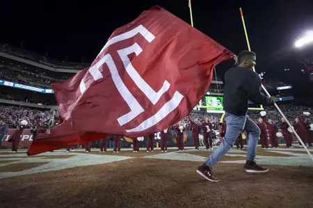 Image of a cheerleader carrying the Templel flag