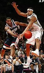 Connecticut's Caron Butler passes around Chevon Troutman in the first half of the Big East final, Saturday night.