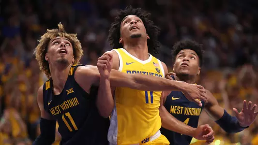 Justin Champagnie boxing out West Virginia defenders.