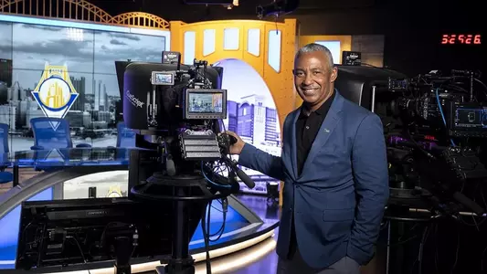 Kevin Smith stands in front of a camera in the Pitt Studios broadcast studio.