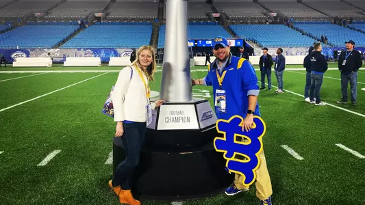 Two Pitt fans stand with the ACC trophy