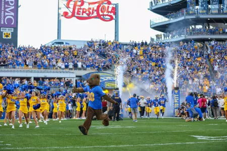 A photo of Roc the panther running out to the tunnel at Acrisure stadium with fans in the background.