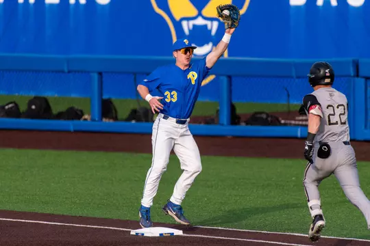 A pitt baseball player catches a throw to make a force out at first base