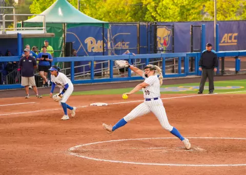 A pitt softball player winds up a pitch