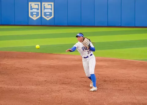 A pitt softball player makes a throw across the infield