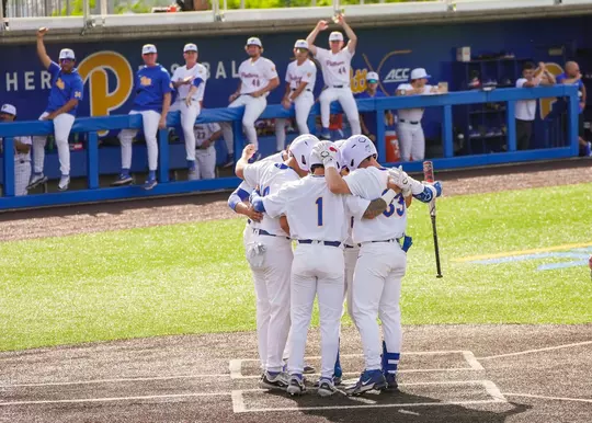Pitt baseball players huddle around home plate after a home run