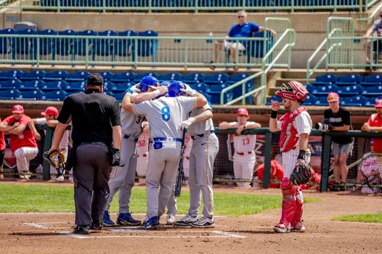 Pitt baseball players huddle around home plate after a home run