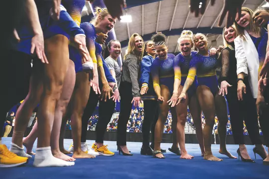 Gymnastics Head Coach Casey Jo MacPherson celebrates in the team huddle after the first ACC victory of the 2024 season with the third highest team score in program history.