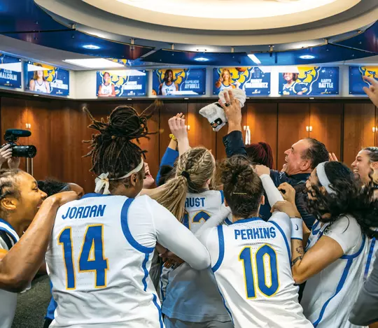 The Pitt Women's Basketball team celebrates their first victory with coach virdi