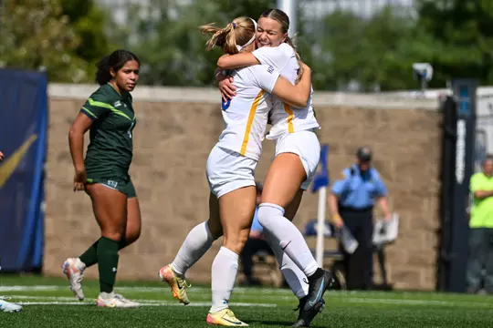 Two Pitt soccer players hug on the field
