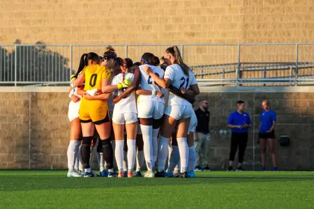 Women's soccer team in huddle before Dartmouth match at Ambrose Urbanic Field