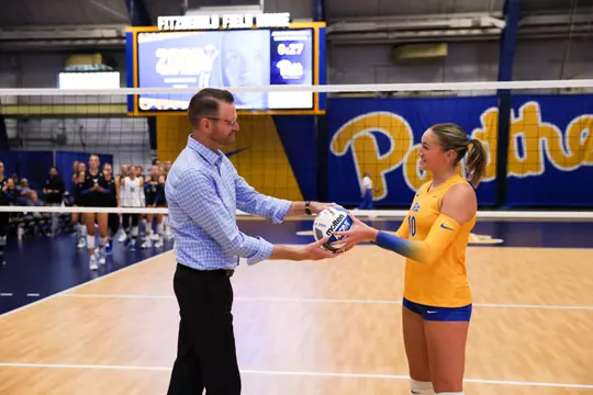 Rachel Fairbanks being handed a volleyball by coach Dan Fisher