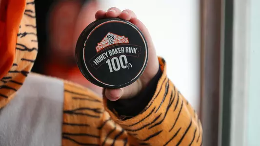fan holds hobey baker 100 logo puck