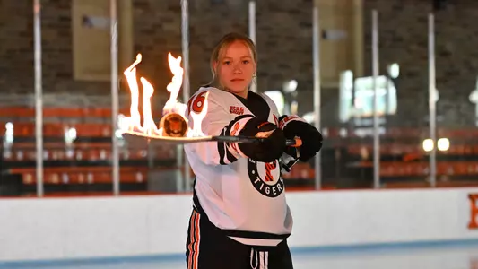 Sarah Fillier holds a hockey stick with a burning blade and puck