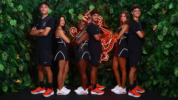 M/W tennis players stand back-to-back against the jungle screen. LtoR: Evan Wen, Bella Chhiv, Tsehay Driscoll, Landon Ardila, Alice Ferlito, Aleksandar Mitric