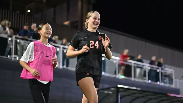 Stella Monberg runs onto the field alongside a ball kid
