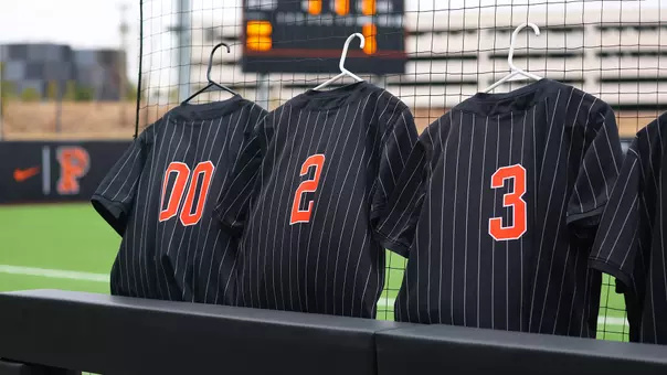 softball uniforms hanging on the protective net