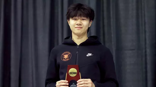 Posed photo of Brandon Lee holding NCAA trophy