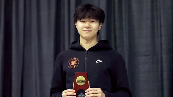 Posed photo of Brandon Lee holding NCAA trophy