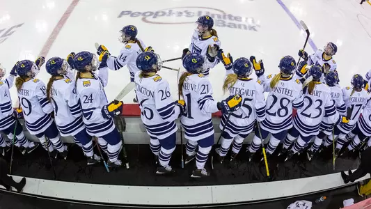 Women's ice hockey players skate through bench line