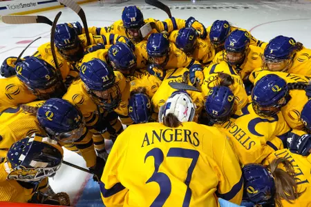 Women's ice hockey huddles around Angers before the game starts