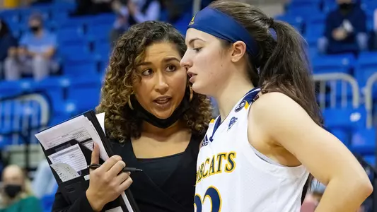 Former assistant coach Kaitlyn Cresencia speaks with Mackenzie DeWees on sidelines