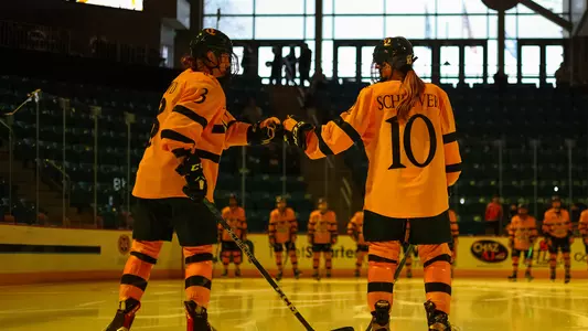 Captain Zoe Boyd and Jess Schryver fist bump on the blue line before a game against Yale