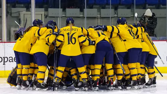 Women's ice hockey huddles around the goal after the national anthem before their matchup against Yale