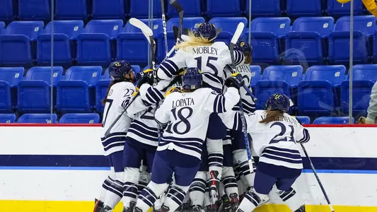 Quinnipiac women's ice hockey celebrates on the boards after Sadie Peart's overtime winning goal
