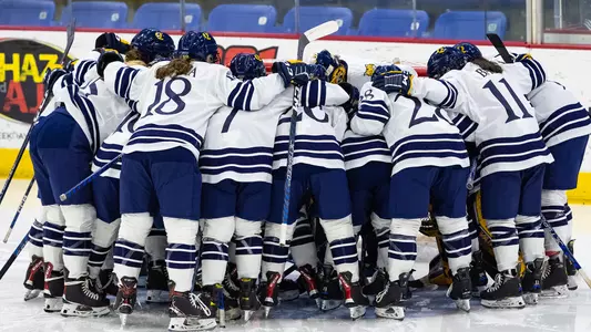 QU women's ice hockey team huddles up around netminder Logan Angers in the crease before a game against St. Lawrence.