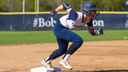A Quinnipiac softball player gets ready to run to home plate while waiting on third base.