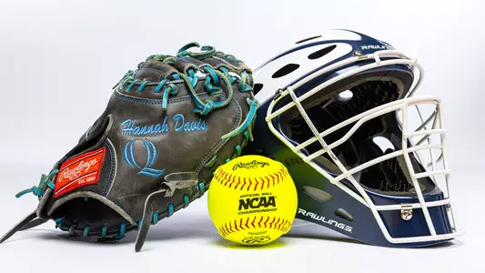 Hannah Davis's helmet, glove and an NCAA branded softball sit on a white backdrop during media day.