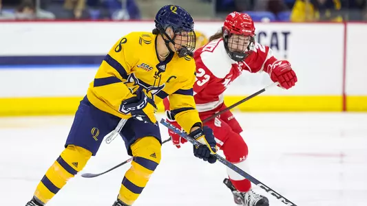 Women's ice hockey captain Lexie Adzija skates with the puck against a Wisconsin defender
