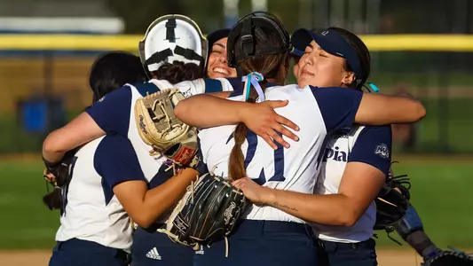 A group of Quinnipiac softball players embrace in a hug after a win against Iona