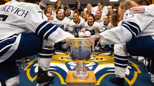Quinnipiac Women's ice hockey celebrates in the locker room with the Nutmeg Championship Trophy.