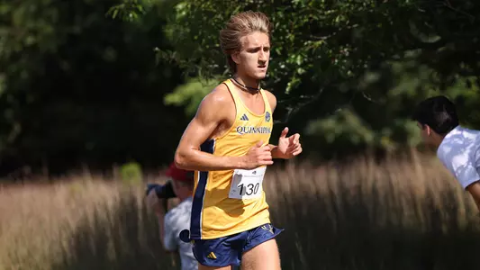 Nolan Kus runs in his gold uniform with Quinnipiac across the chest.