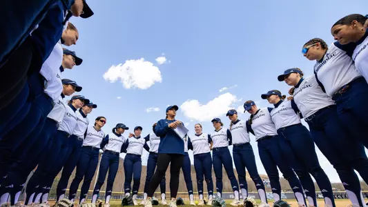 Softball team huddle with Head Coach Hillary Smith in the center (March 25, 2025)
