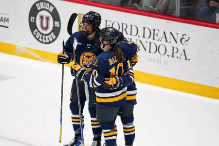 Ella Johnson and Avery Bairos celebrate with Emerson Jarvis on her hat trick (1.10.26 in Schenectady, N.Y.)