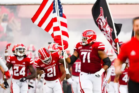 George Jackson runs out the tunnel with an American Flag September 23, 2023 Louisiana vs University of Buffalo Football in Lafayette, LA at Cajun Field. Final score Louisiana 45 Buffalo 38. Photo by Benjamin R. Massey/Ragin Cajun Athletics