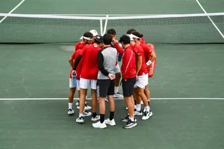 The men's tennis team huddles before a match against Troy